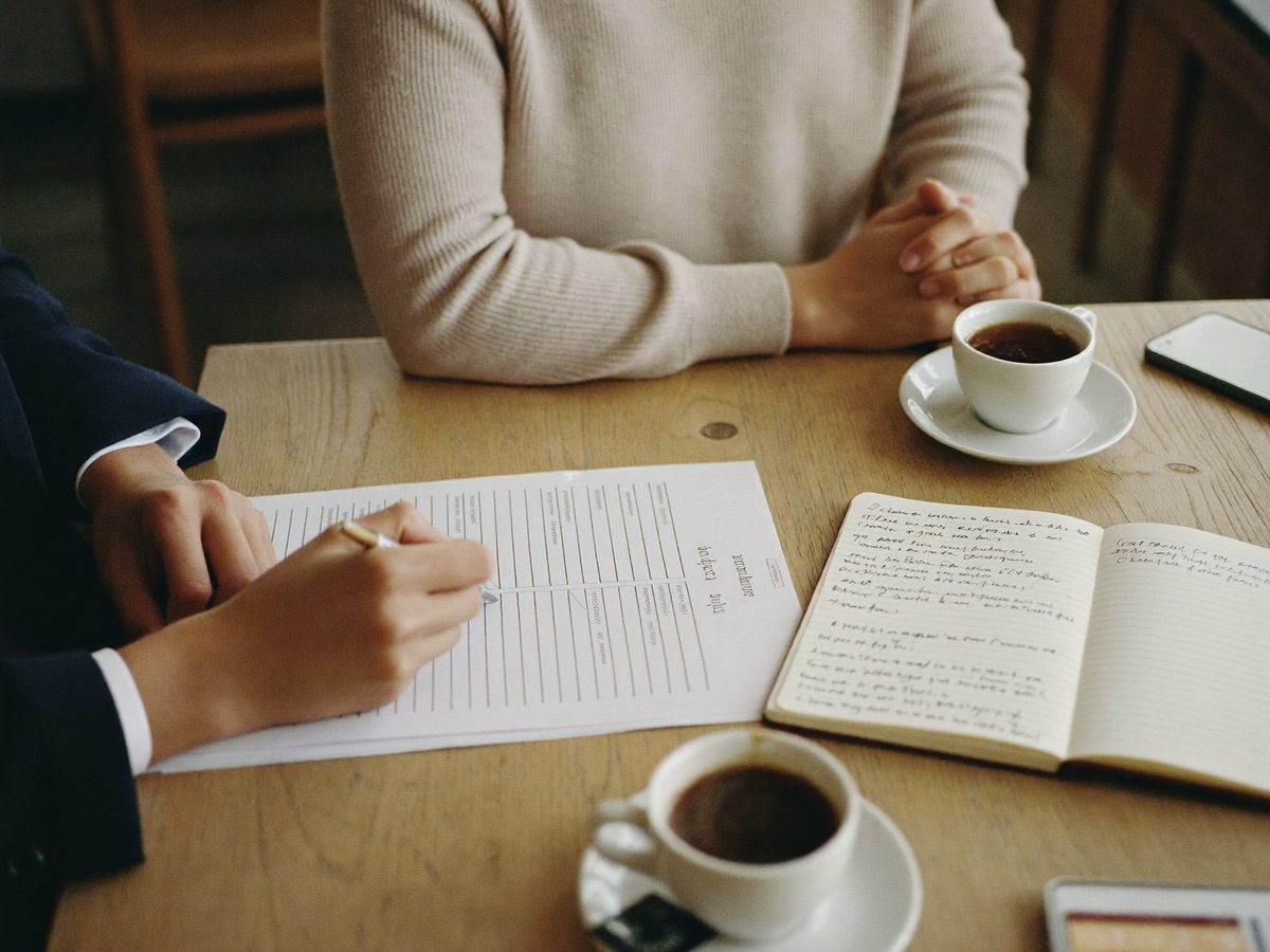 A conversation over coffee, with notes and a printed report on the table